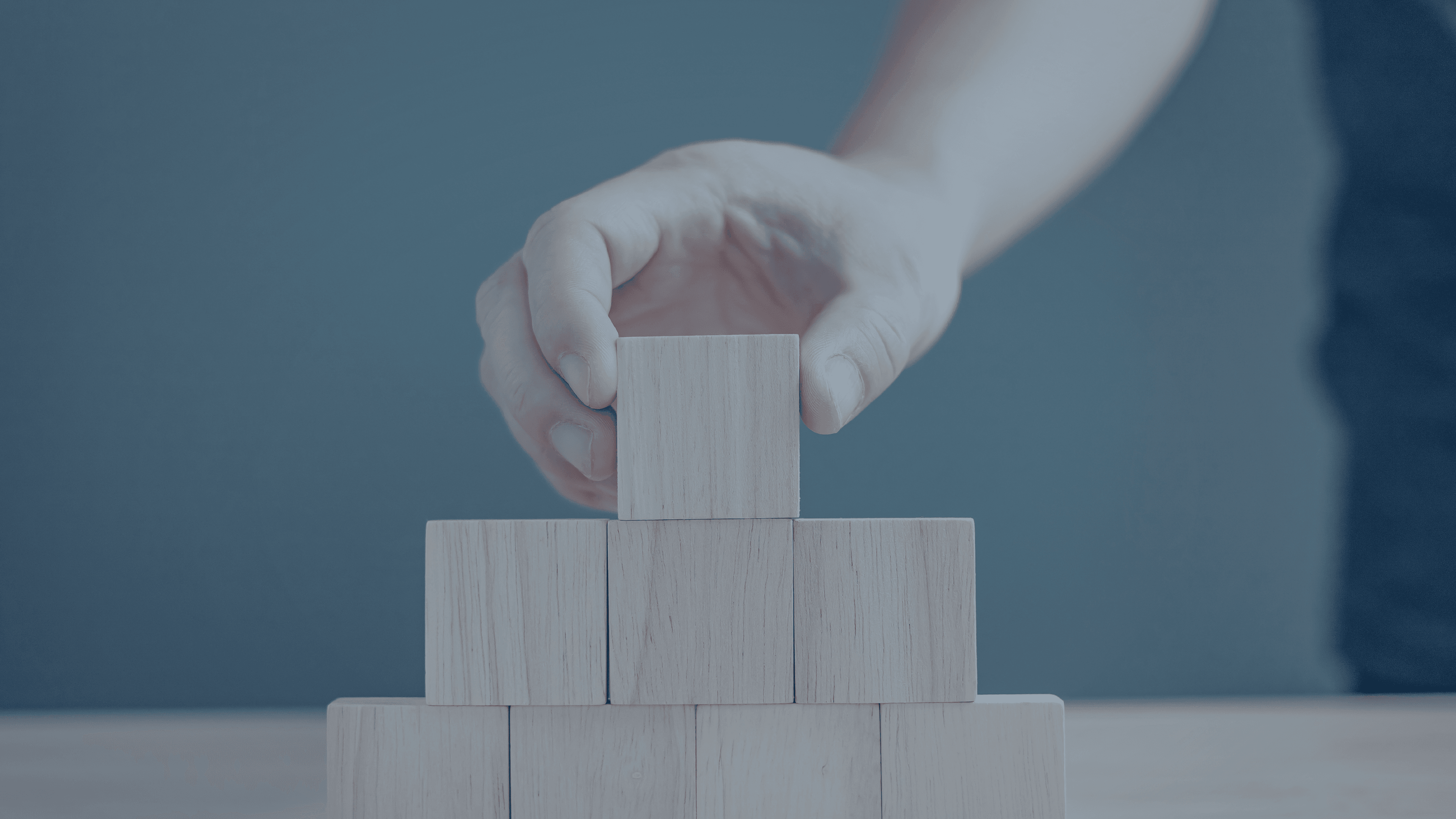 Opbygning af fundament med træklodser, der symboliserer finansiel struktur og systematisk økonomiopbygning.